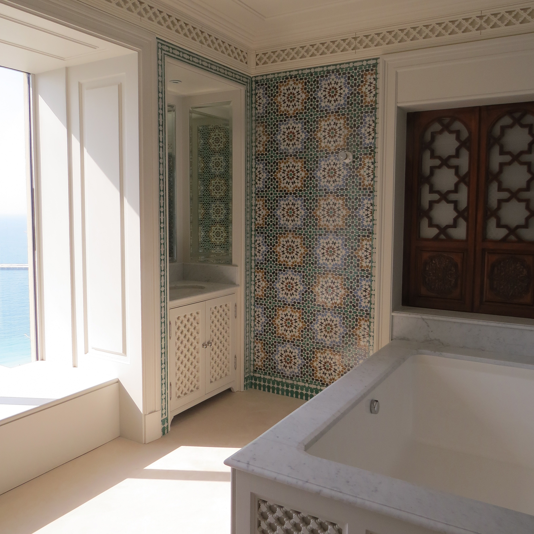 Each craft was carefully co-ordinated to ensure that the handmade zellij tiles in the bathroom terminate symmetrically on borders. Carved panels screen the AC grilles.